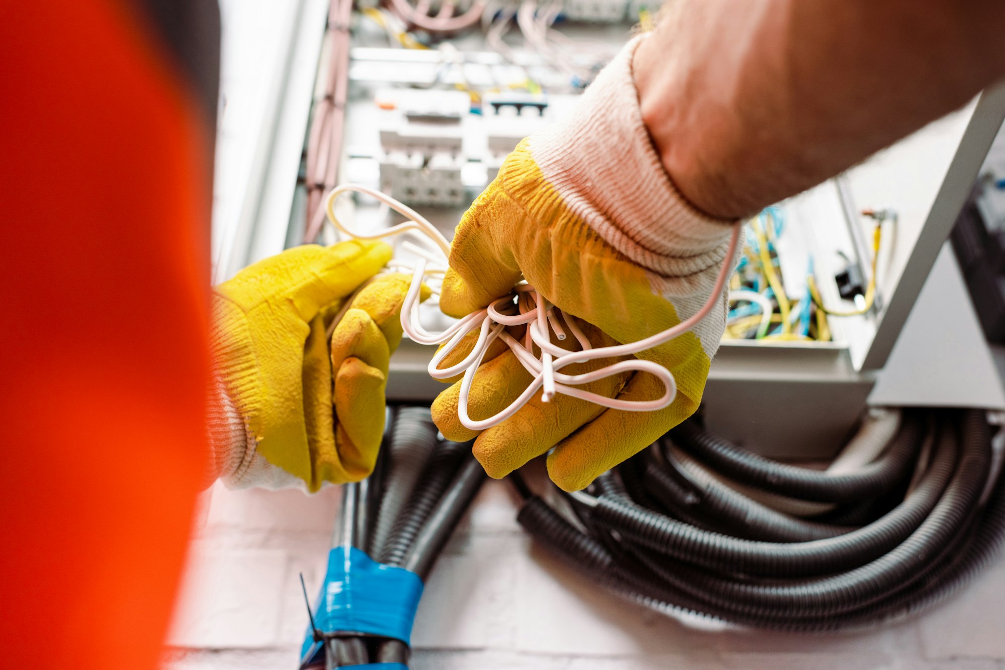 Cropped view of electrician in gloves holding wires near electrical box.jpg