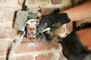 Man working on electric socket by brick wall.jpg